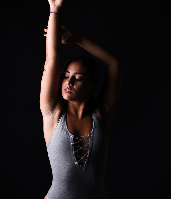 Serene woman performing a balance pose in a dark ambient studio.